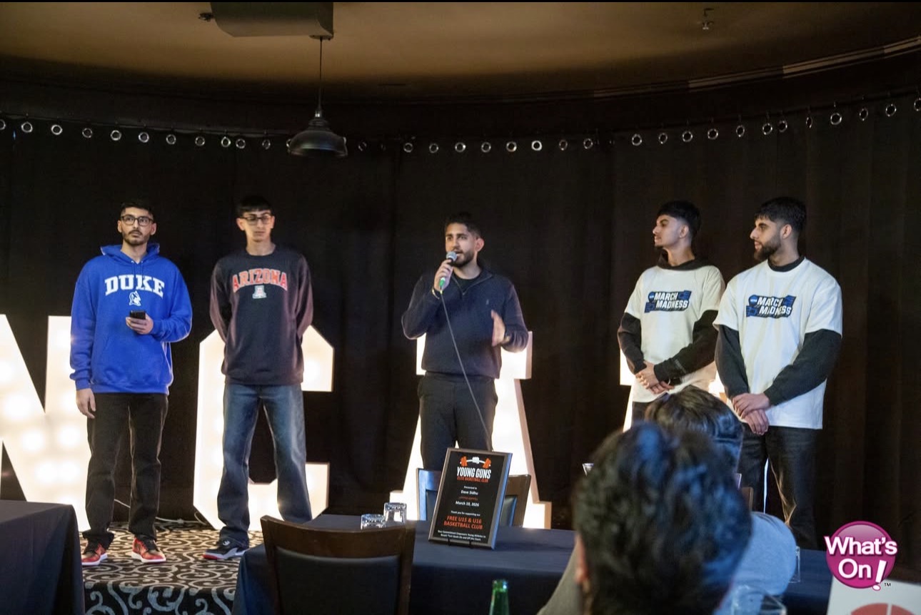 Arsh Kaler speaking with a microphone alongside youth basketball club members at a community fundraiser